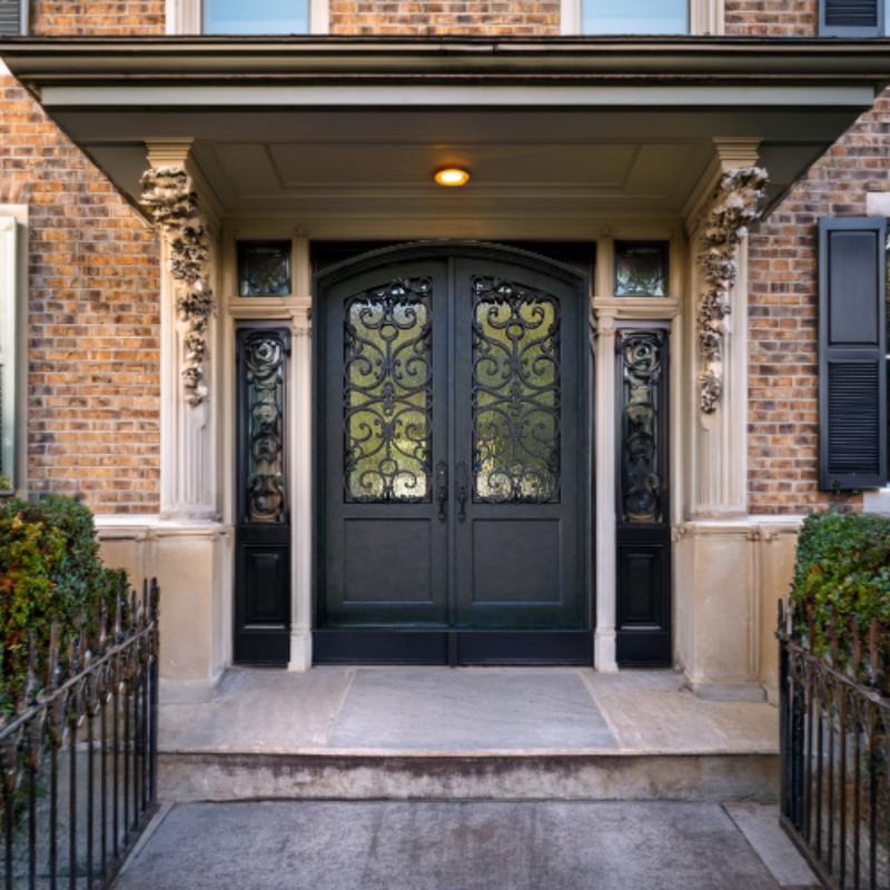 Antique iron door with arched top and scrollwork grille detail