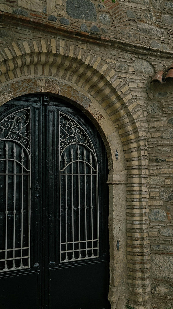 Double iron doors with arched transom and gothic scrollwork